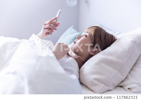 Woman looking at smartphone in bed 117862315