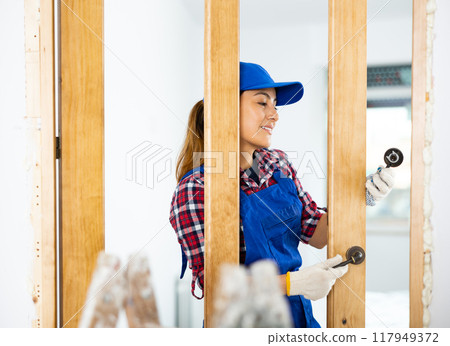 Positive female worker assembling door handle 117949372