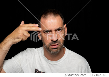 Bearded hispanic man around 40 years old isolated over dark background making gun gesture with his hand pointing to his head. 117167189