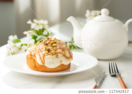 Cinnamon roll bun with icing on plate 117342917