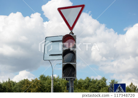 A bright red traffic light is currently hanging from a tall pole 117348720