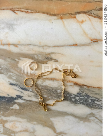 Golden coloured necklace and rings on the marble table . High quality photo 118424866