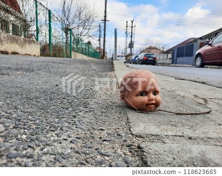 A doll head sitting in the street 118623685