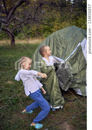 mother and little daughters are setting up a tourist tent in  forest, camping with children 118650857