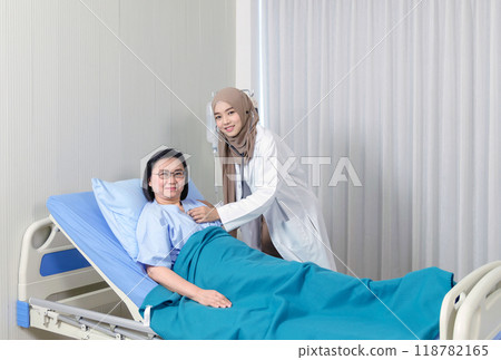 Young asian muslim female doctor using stethoscope checking to elderly patient sitting in bed at hospital. Medicine and health care safe concept. 118782165