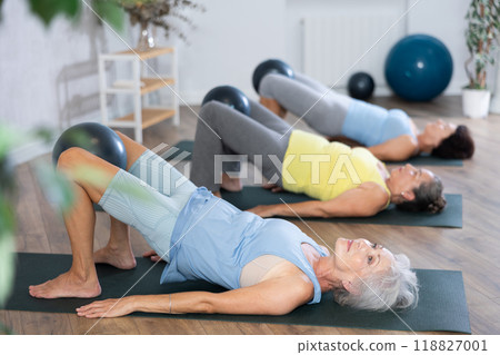 Elderly women perform softball exercises lying on floor, workout for beautiful figure, toned body 118827001