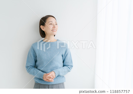 Smiling woman standing by the window 118857757