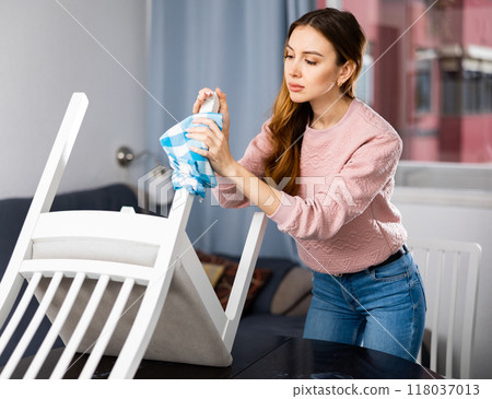 Young woman wipes a chair with a damp cloth 118037013