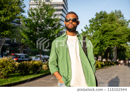 Serious african man strolling on sidewalk, walking to college, heading home after university classes 118102944