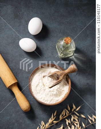 Oatmeal in a wooden bowl with eggs, rolling pin and oli on a dark background. 118148177