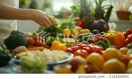 Person arranging a variety of fresh vegetables on table 118368041