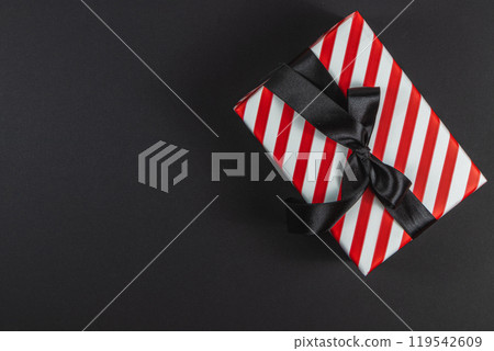 Red striped box with bow on black background for black friday new year 119542609