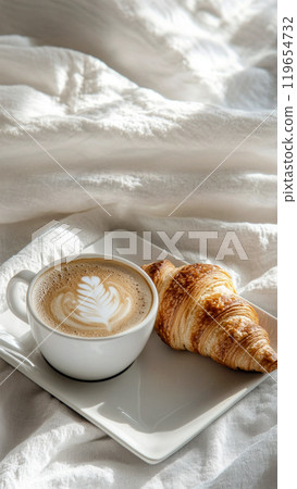 A white cup of cappuccino with a croissant on an elegant rectangle white plate 119654732