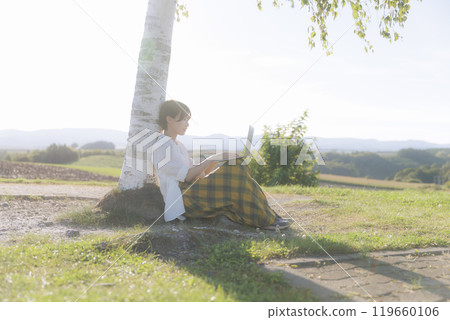 A young woman sitting on a bench and using a laptop 119660106