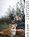 girl and dog near basket  with juicy apples in the garden 119772925