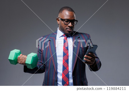 African businessman in suit works online with phone in hand and does sports at the same time, business and sports 119884211