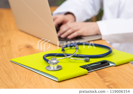 A senior female doctor in a white coat doing desk work 119006354