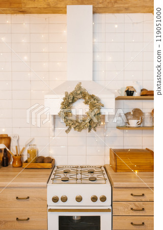 Kitchen with a white stove and christmas wreath. Festive cozy atmosphere 119051000