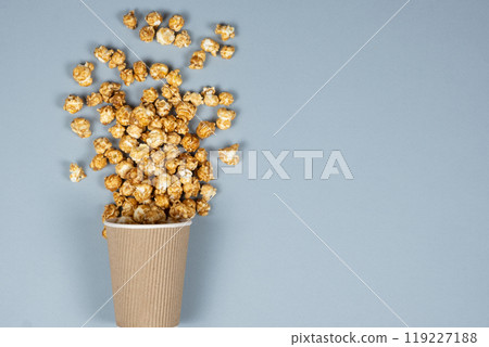 Sweet caramelized popcorn spilled out of the glass. Copy space for text. 119227188