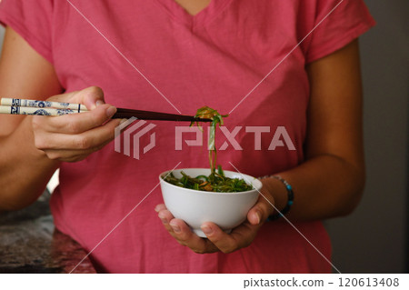 Girl holding a cup of wakame in her hands 120613408