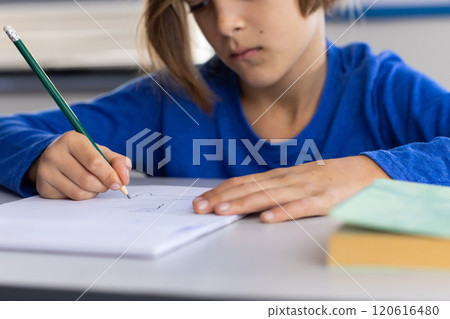 In school, boy writing in notebook, focusing on classroom assignment 120616480