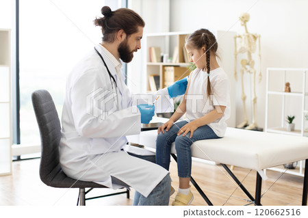 Doctor carefully administers vaccine to young girl in clinic 120662516