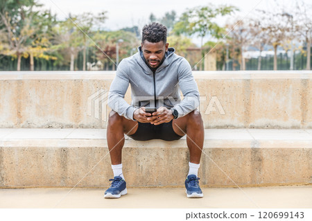 Black sportsman using smartphone on stairs 120699143