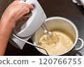 Chef whisking ingredients in bowl with electric mixer 120766755