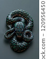 A green and black snake brooch is resting on top of a table 120956450