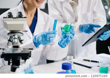 Young scientists conducting research investigations in a medical laboratory, a researcher in the foreground is using a microscope 120975169