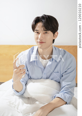 A man in his 20s sitting on a bed and posing 120010210