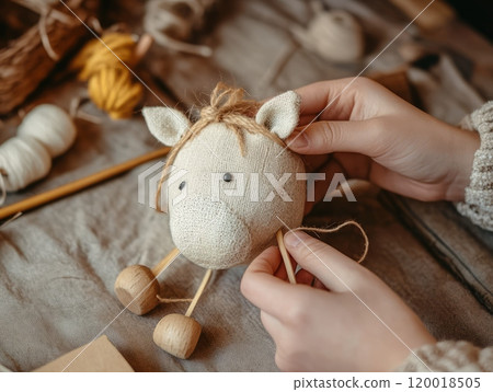 Close-up of hands sewing a handmade fabric toy in a craft workshop. 120018505