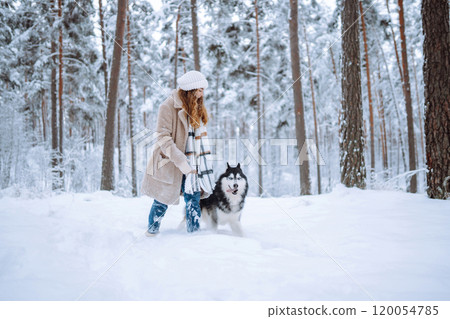 Beautiful young woman plays with her dog in winter forest. First snow Friendship. Outdoor recreation 120054785