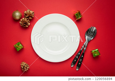 Christmas table setting decorated with empty plate, golden pine cones, and gift boxes 120056894