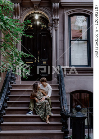 A Lovely Couple Sitting Together on the Steps of a Charming Brownstone in an Urban Setting 120092187