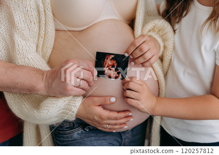 Family bonds grow stronger as they cherish the ultrasound of their soon-to-arrive baby 120257812