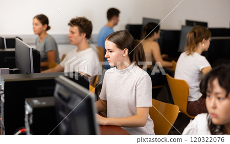 Interested teenage students during lesson in computer room of library. Focus on young girl 120322076