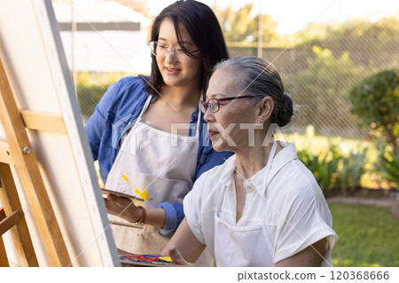 Painting on canvas, asian granddaughter and grandmother enjoying outdoor art activity 120368666