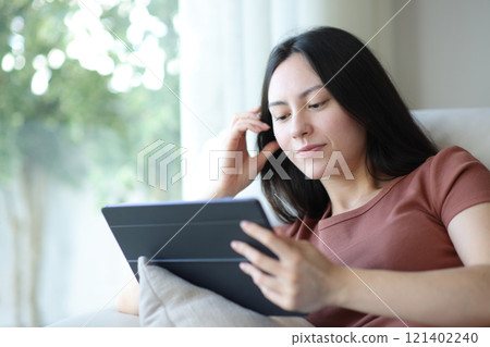 Asian woman using tablet on a couch 121402240