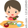 A smiling woman eating Japanese food such as grilled fish 121418949