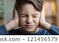 Scared boy kid victim of domestic violence keeps hand to head covering ears, eyes closed, feeling discomfort and emotional stress. Sad child feels scared, looks hopeless due of home abuse 121456579