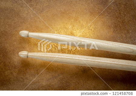 classic 5A wooden drumsticks against backlit drum goat skin 121458708