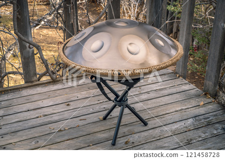 handpan drum on a stand outdoors, a modern, melodic percussion instrument made of steel, known for its soothing, resonant tones 121458728