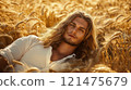 An attractive male model, wearing white silk pajamas, lying in the middle of a golden wheat field.  121475679