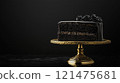 Black frosted cake with a gold stand, cut in half, against a dark background. 121475681