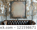 Old abandoned room with leather couch and blank picture frame hanging on a dirty wall. Copy space. 121598671