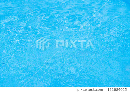 Serene blue water surface with gentle ripples and a soft sun glow 121684025