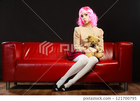 childlike woman and teddy bear sitting on couch 121700795