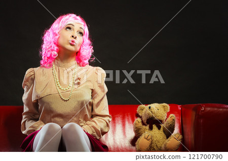 childlike woman and teddy bear sitting on couch 121700790