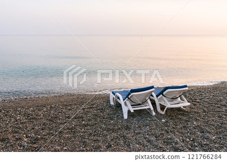 Two plastic sun beds on the sea beach at sunrise. Summer vacation concept. 121766284